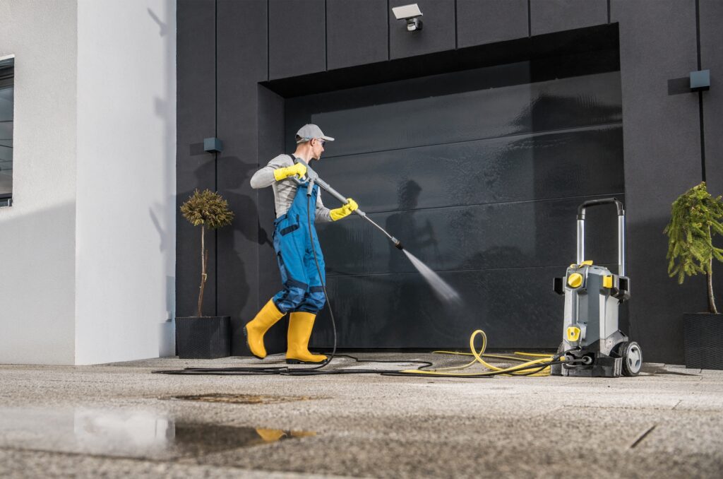 Worker power washing a garage door